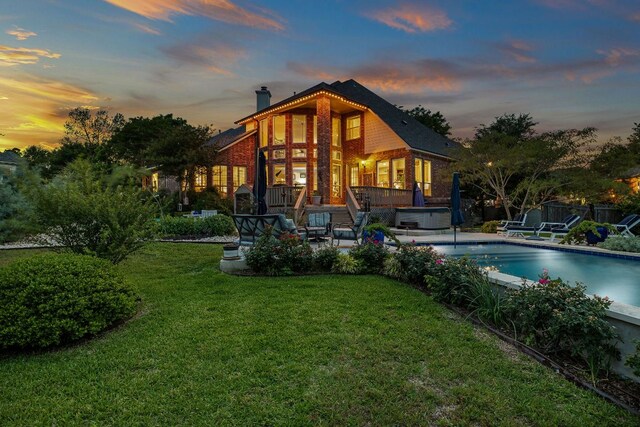 rear view of house featuring a lawn, a hot tub, a patio area, and a chimney