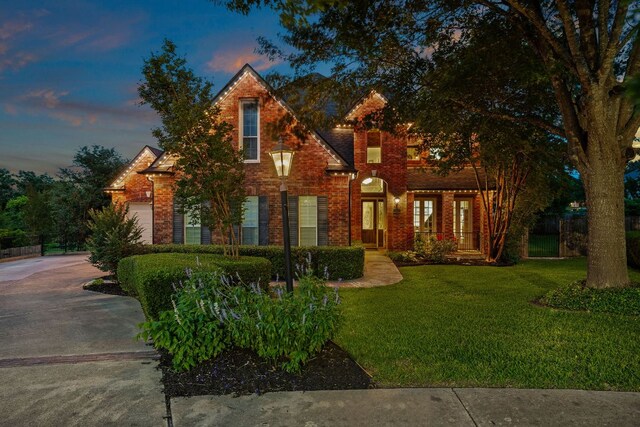 view of front facade featuring concrete driveway, a front lawn, and brick siding