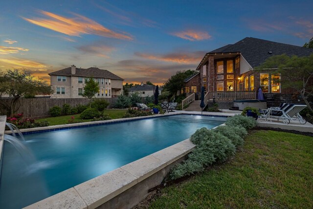 view of swimming pool featuring a deck, fence, a fenced in pool, a yard, and a patio