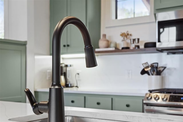 details with light countertops, stainless steel appliances, green cabinetry, and a sink