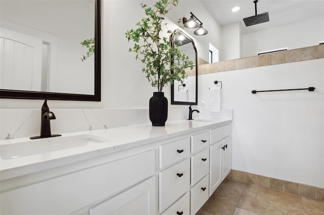 bathroom featuring double vanity, a sink, baseboards, and stone tile flooring