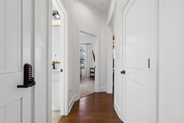 hall featuring baseboards and dark wood-style flooring