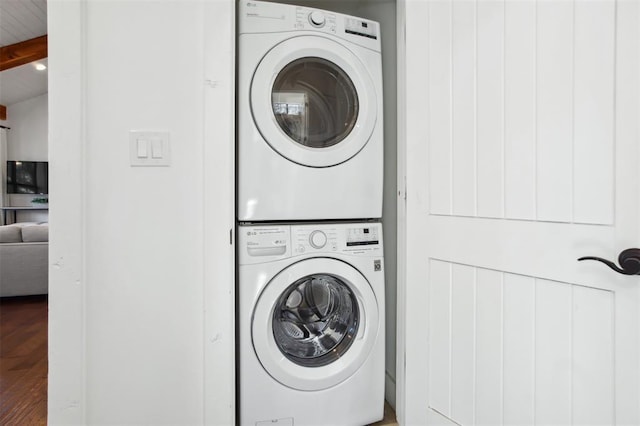 clothes washing area with wood finished floors, laundry area, and stacked washer / drying machine
