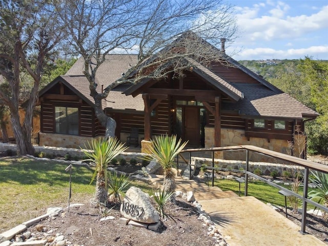cabin with a shingled roof and stone siding