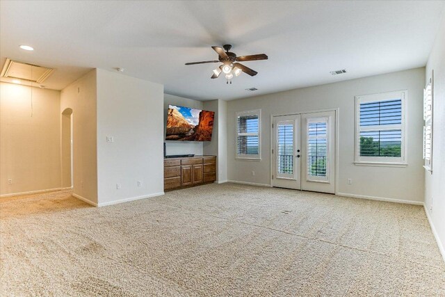 unfurnished living room with carpet floors, plenty of natural light, a ceiling fan, and attic access
