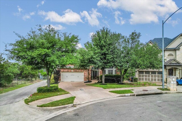 view of property hidden behind natural elements featuring driveway and a garage