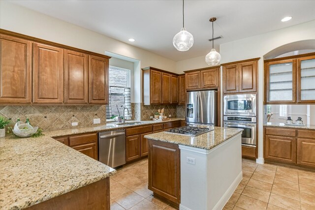 kitchen with light tile patterned flooring, appliances with stainless steel finishes, a sink, and tasteful backsplash