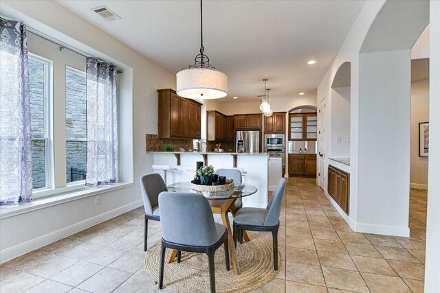 dining space featuring light tile patterned floors, baseboards, plenty of natural light, and visible vents