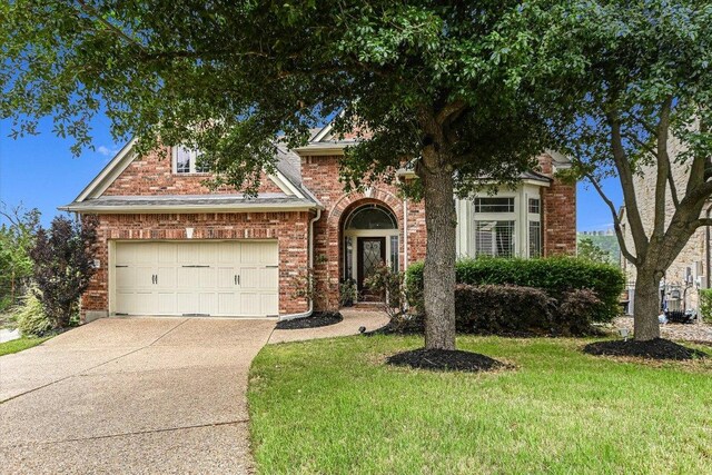 view of front of house with concrete driveway, brick siding, a front lawn, and a garage