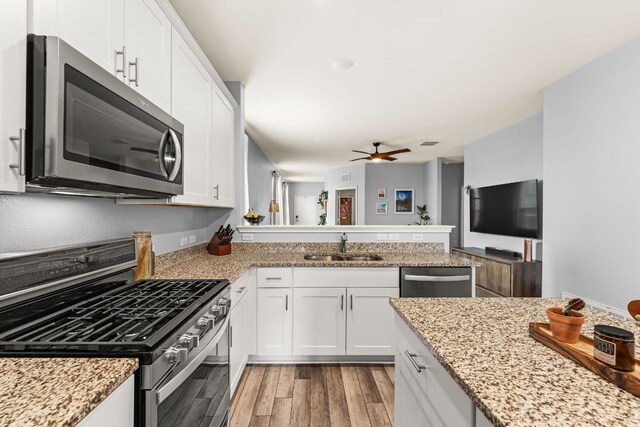 kitchen featuring ceiling fan, appliances with stainless steel finishes, a sink, light wood-style floors, and white cabinetry