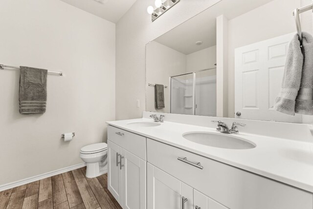 full bathroom with double vanity, a sink, wood finished floors, and toilet
