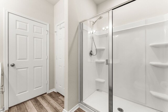 full bathroom featuring baseboards, wood finished floors, and a shower stall