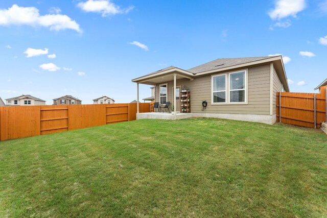 back of property with a fenced backyard and a lawn