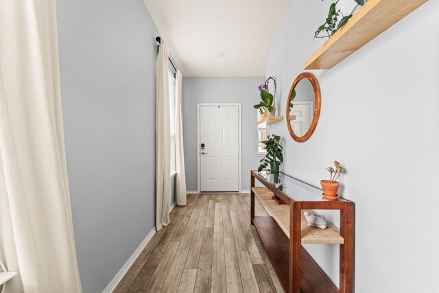 hallway featuring baseboards and light wood finished floors