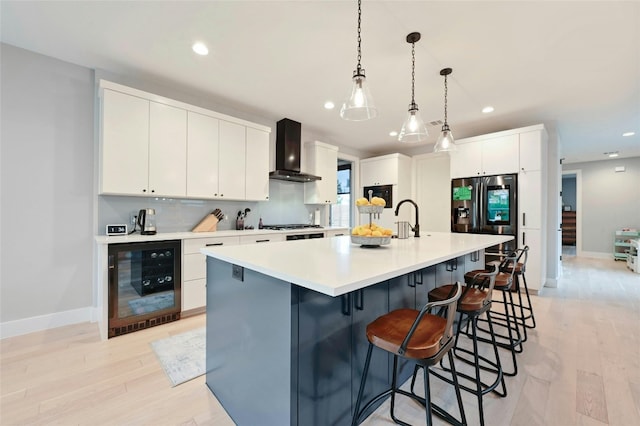 kitchen with beverage cooler, baseboards, wall chimney exhaust hood, and light wood-style floors