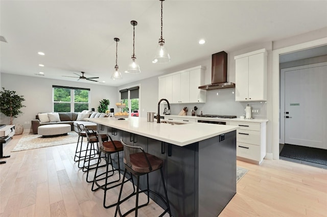 7103 Daugherty St, Austin, TX 78757 - kitchen with wall chimney exhaust hood, light wood finished floors, recessed lighting, white cabinets, and a breakfast bar area