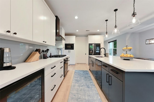 7103 Daugherty St, Austin, TX 78757 - kitchen featuring appliances with stainless steel finishes, light wood-type flooring, wall chimney range hood, pendant lighting, and recessed lighting