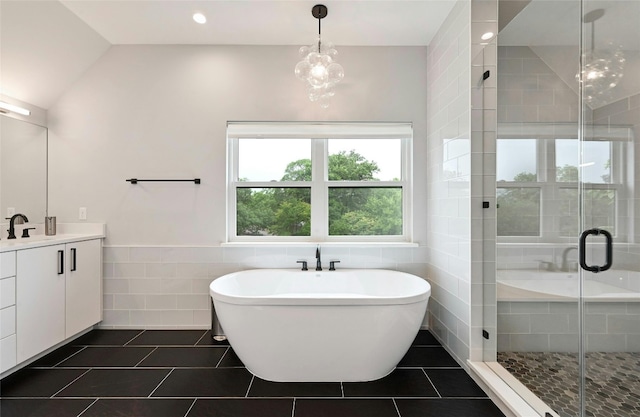 bathroom featuring tile patterned flooring, vanity, tile walls, a shower stall, and a soaking tub