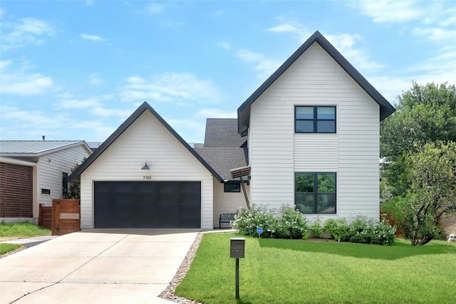 modern farmhouse with concrete driveway, an attached garage, and a front yard