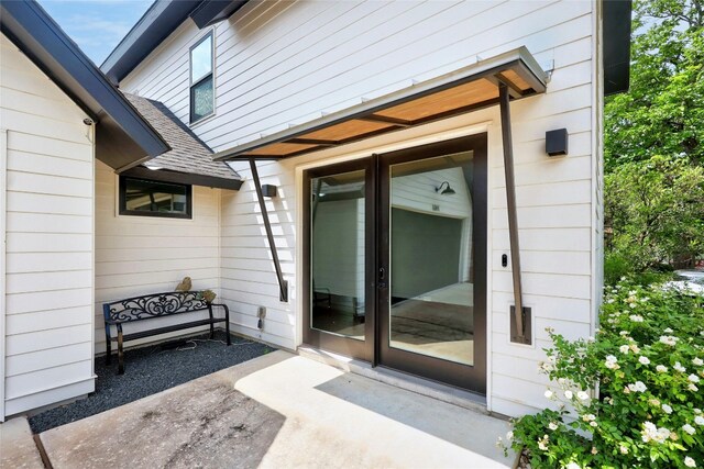 property entrance with a shingled roof, a patio area, and french doors