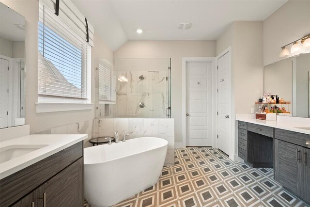 bathroom with recessed lighting, two vanities, a shower stall, vaulted ceiling, and a soaking tub
