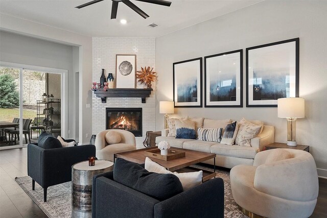 living room with a fireplace, a ceiling fan, wood finished floors, and visible vents