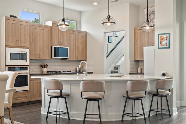 kitchen featuring dark wood-type flooring, light countertops, a sink, appliances with stainless steel finishes, and backsplash