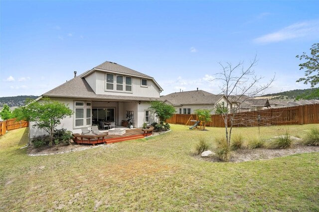 back of house featuring roof with shingles, a deck, a fenced backyard, a yard, and stucco siding