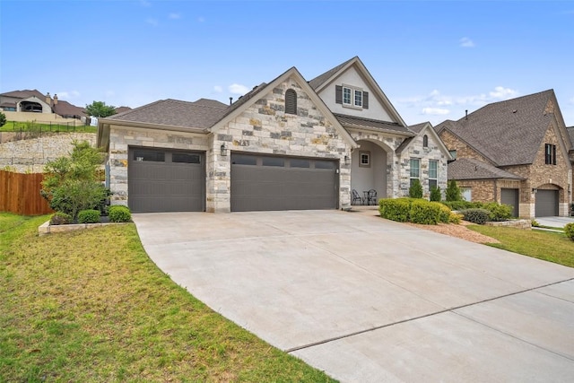 french country home featuring fence, a front lawn, stone siding, a garage, and concrete driveway