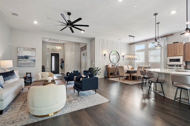 living area featuring recessed lighting, ceiling fan with notable chandelier, dark wood-style floors, and visible vents