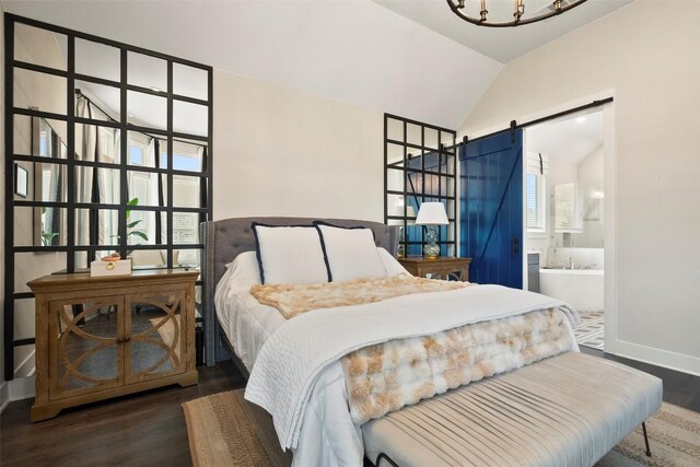 bedroom with wood finished floors, baseboards, a barn door, connected bathroom, and vaulted ceiling