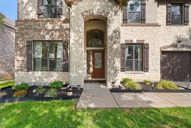 view of exterior entry featuring an attached garage and stone siding