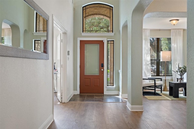 entrance foyer featuring baseboards, arched walkways, and wood finished floors