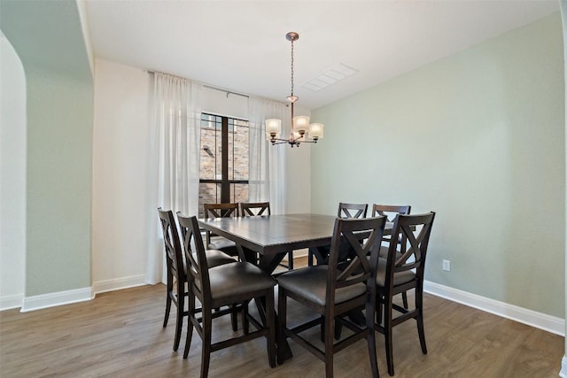 dining space with an inviting chandelier, baseboards, wood finished floors, and visible vents