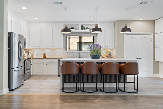 kitchen with visible vents, appliances with stainless steel finishes, a sink, white cabinets, and a breakfast bar