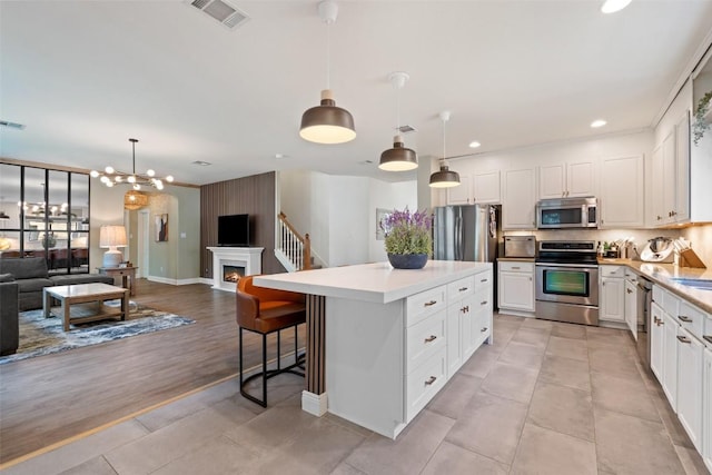 kitchen with a kitchen island, visible vents, appliances with stainless steel finishes, light countertops, and open floor plan