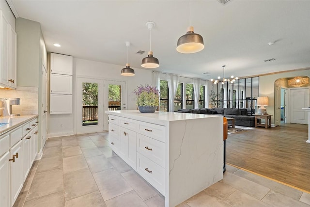 kitchen featuring an inviting chandelier, plenty of natural light, a kitchen island, and visible vents