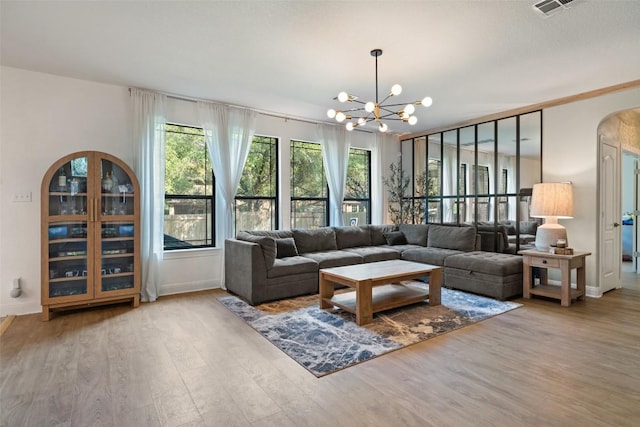 living area with baseboards, visible vents, wood finished floors, and a notable chandelier