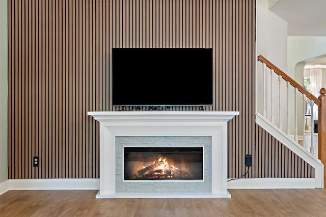 interior details with baseboards, a glass covered fireplace, and wood finished floors