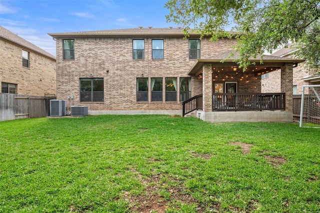rear view of house featuring a lawn, central AC unit, a fenced backyard, and brick siding