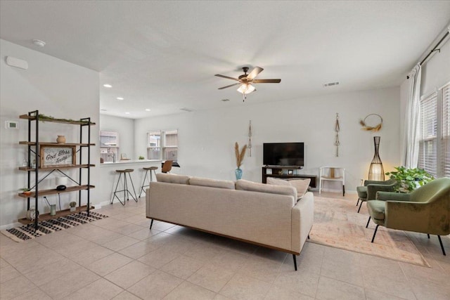 living area with light tile patterned floors, a ceiling fan, visible vents, baseboards, and recessed lighting