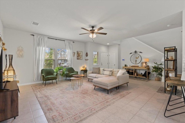 living area featuring light tile patterned flooring, baseboards, a ceiling fan, and visible vents
