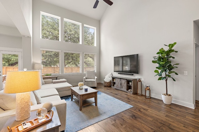 living room with baseboards, ceiling fan, wood finished floors, and high vaulted ceiling