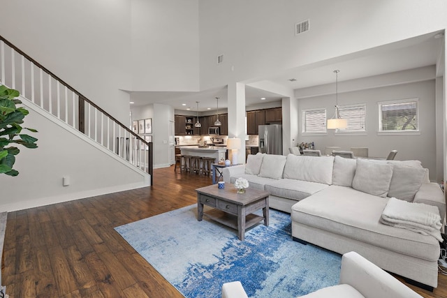 living room with visible vents, dark wood-style floors, and stairway