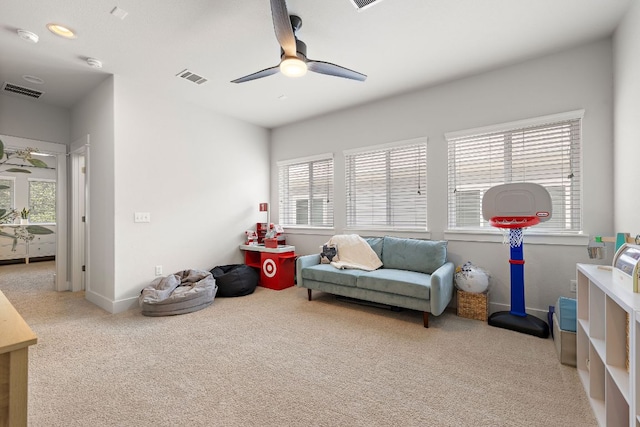 living area with plenty of natural light, a ceiling fan, and visible vents