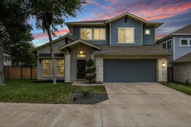 traditional-style house featuring fence, a front lawn, stone siding, a garage, and driveway