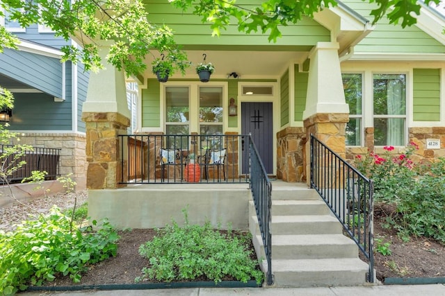 doorway to property featuring covered porch and stone siding