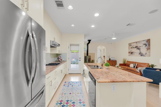 kitchen featuring freestanding refrigerator, gas cooktop, arched walkways, a sink, and dishwasher