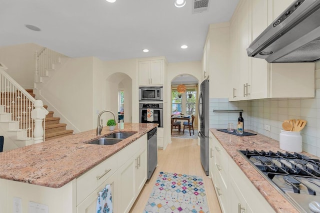 kitchen featuring visible vents, arched walkways, under cabinet range hood, a sink, and stainless steel appliances