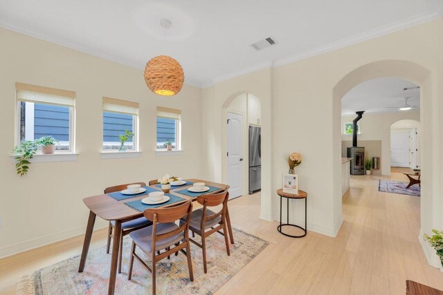 dining room featuring arched walkways, visible vents, and light wood-style flooring
